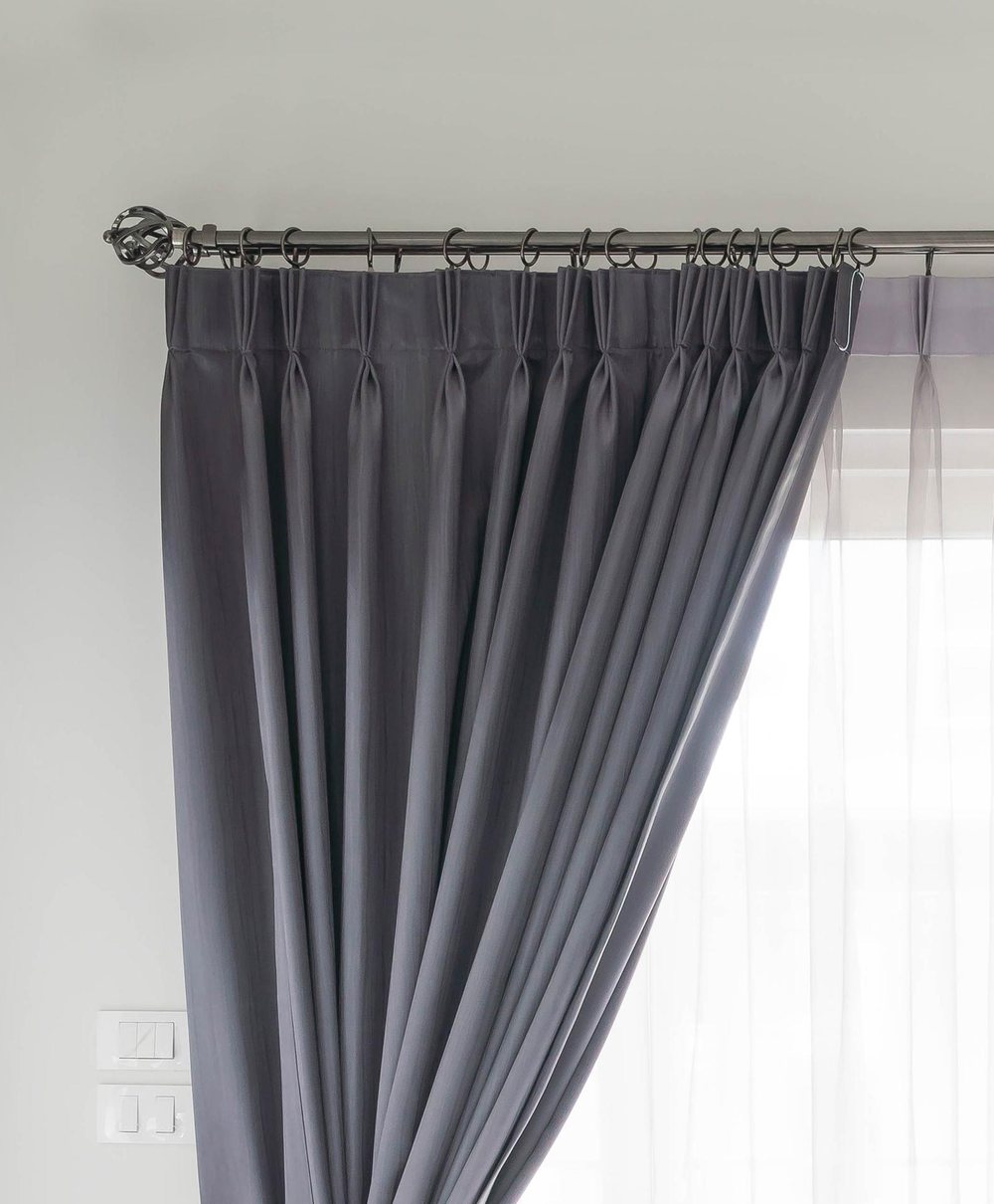 Cortina cinza presa em varão com ponteira decorativa